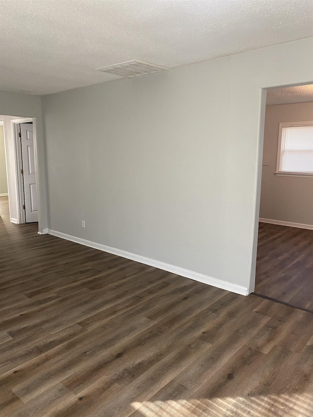 spare room featuring a textured ceiling and dark hardwood / wood-style floors