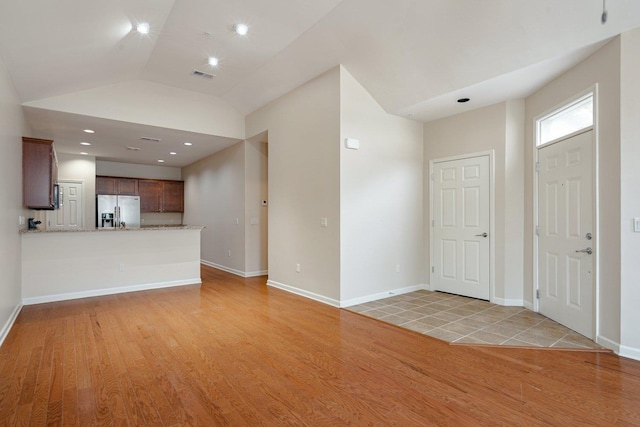 unfurnished living room with light wood-type flooring and vaulted ceiling