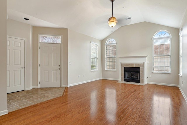 unfurnished living room featuring a fireplace, a wealth of natural light, light wood-type flooring, and ceiling fan