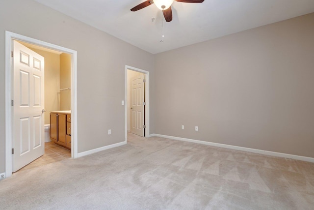 unfurnished bedroom featuring ceiling fan, light colored carpet, a spacious closet, and ensuite bathroom