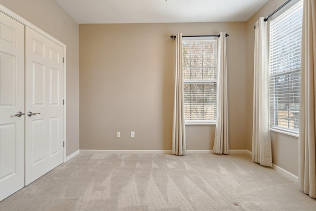 unfurnished bedroom featuring light carpet and a closet