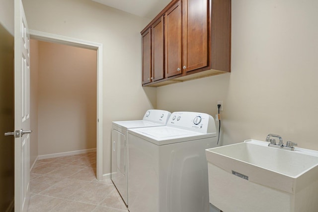 clothes washing area featuring separate washer and dryer, sink, light tile patterned floors, and cabinets