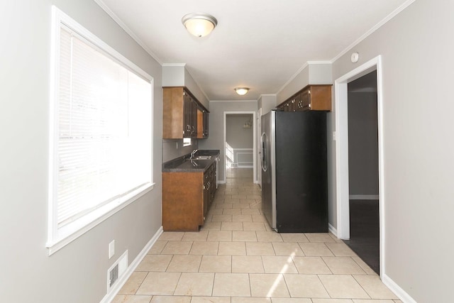 kitchen featuring light tile patterned flooring, ornamental molding, sink, and stainless steel refrigerator