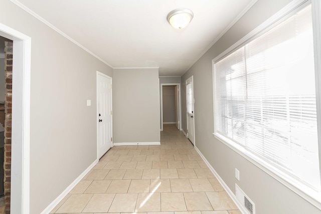 hallway with a wealth of natural light, crown molding, and light tile patterned flooring