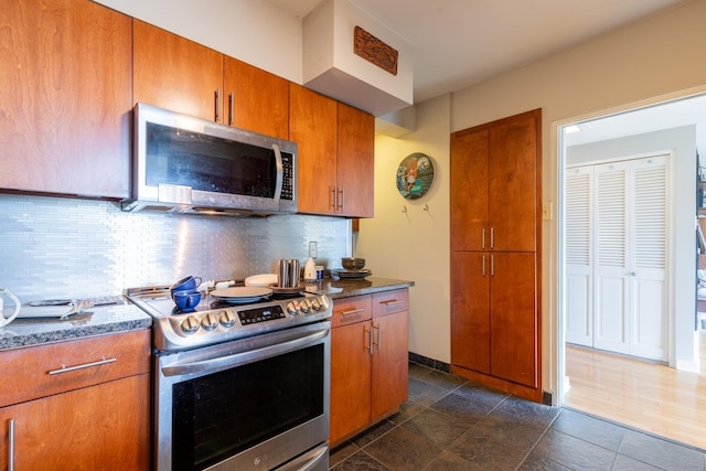 kitchen featuring stainless steel appliances, dark stone counters, and tasteful backsplash