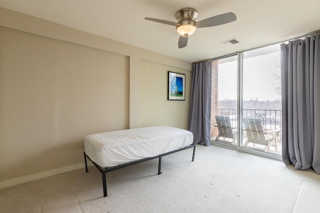 bedroom with access to exterior, ceiling fan, light carpet, and a wall of windows