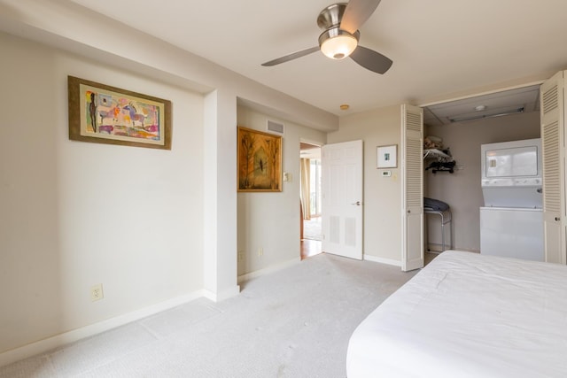 carpeted bedroom with a closet, stacked washer / drying machine, and ceiling fan