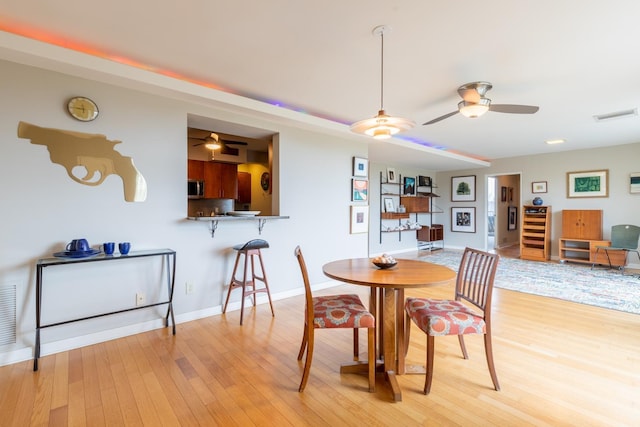 dining room with ceiling fan and light hardwood / wood-style flooring