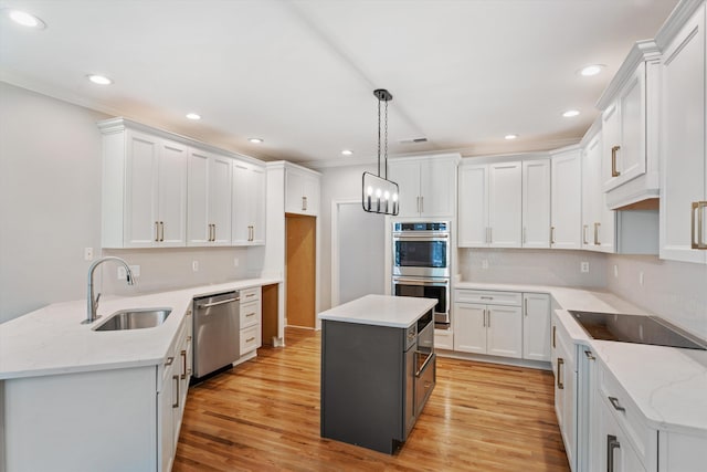 kitchen featuring stainless steel appliances, sink, a center island, white cabinetry, and hanging light fixtures