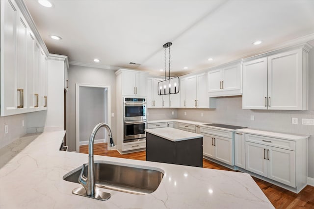 kitchen with light stone counters, stainless steel double oven, sink, decorative light fixtures, and white cabinetry