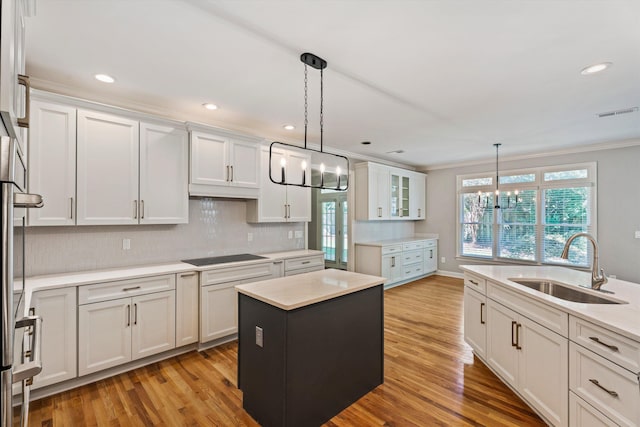 kitchen with a center island, white cabinets, pendant lighting, and sink