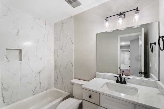 full bathroom with tiled shower / bath, vanity, and toilet