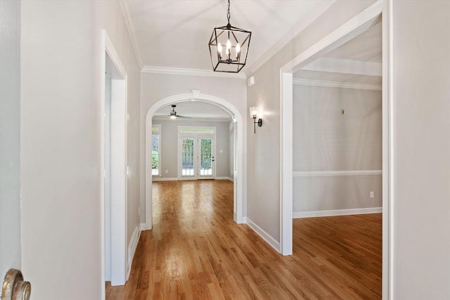 hallway featuring light hardwood / wood-style floors, ornamental molding, and an inviting chandelier