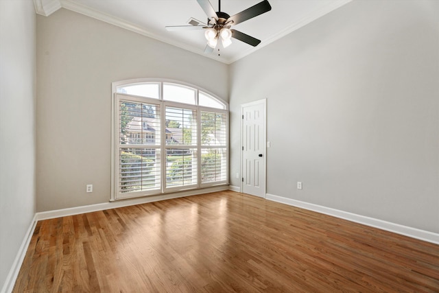 spare room featuring hardwood / wood-style floors, ceiling fan, ornamental molding, and a towering ceiling