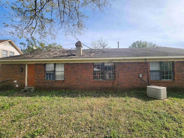 back of house featuring central AC unit and a lawn