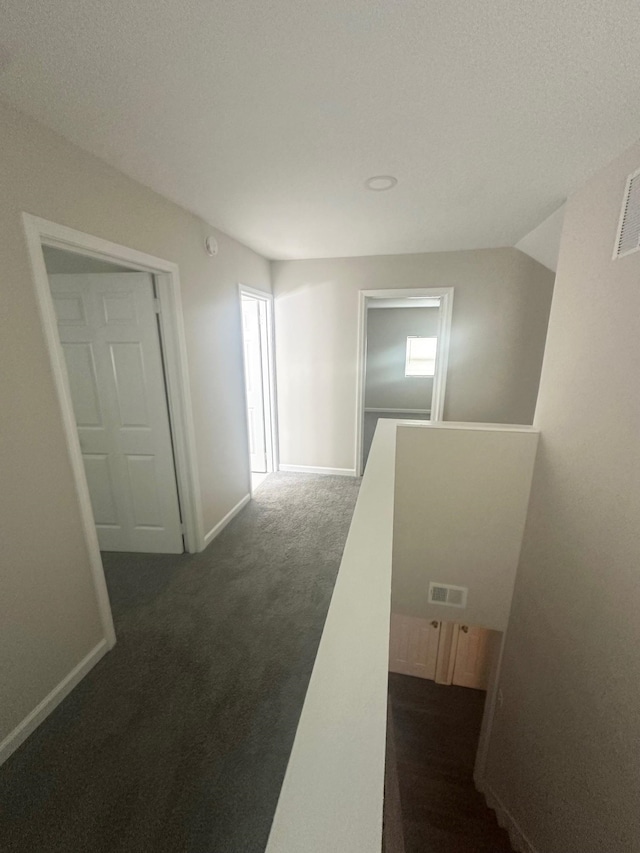 hallway featuring dark carpet and vaulted ceiling