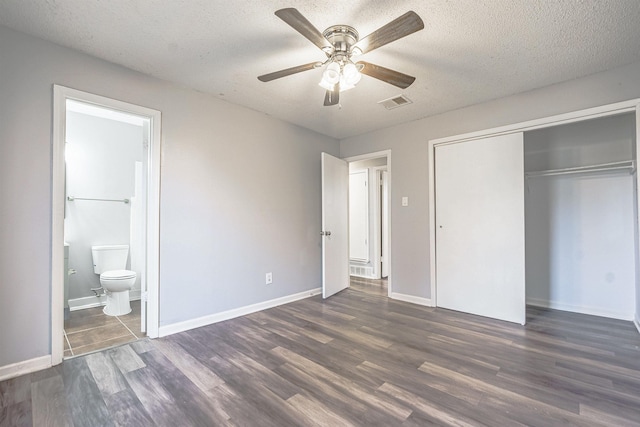 unfurnished bedroom featuring ceiling fan, dark hardwood / wood-style floors, a textured ceiling, and connected bathroom