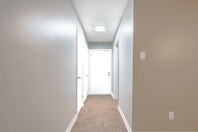 hall featuring tile patterned floors and a textured ceiling