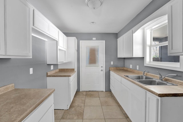 kitchen featuring white cabinets, light tile patterned floors, and sink