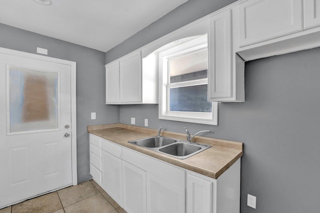 kitchen with white cabinets, light tile patterned floors, and sink