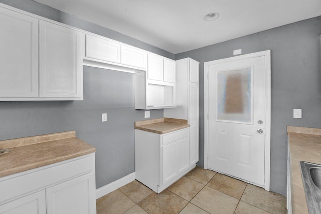 kitchen featuring sink, white cabinetry, and light tile patterned flooring