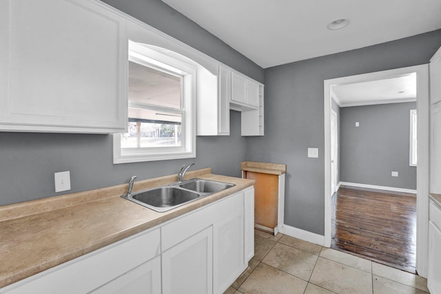 kitchen with white cabinets, light tile patterned flooring, and sink