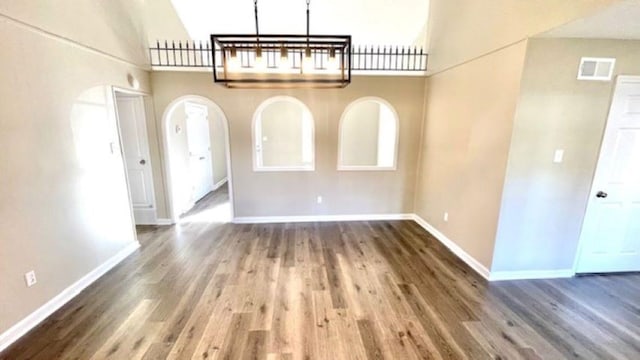 unfurnished dining area with dark hardwood / wood-style floors and a high ceiling