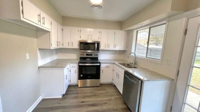 kitchen featuring white cabinetry, sink, stainless steel appliances, and wood-type flooring