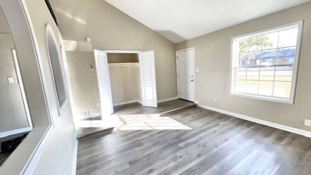 unfurnished bedroom with a textured ceiling, light hardwood / wood-style floors, and lofted ceiling