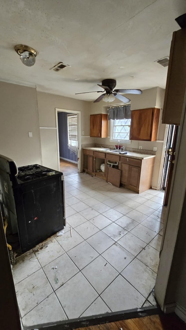 kitchen featuring light tile patterned flooring, plenty of natural light, black range, and ceiling fan