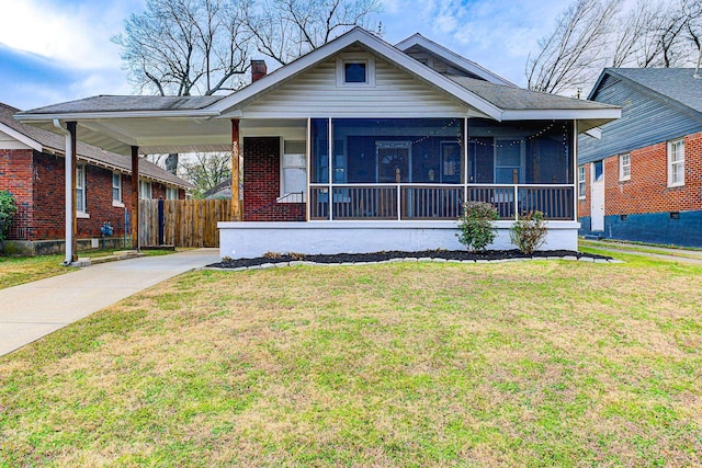 bungalow-style house with a carport, a front lawn, and a sunroom