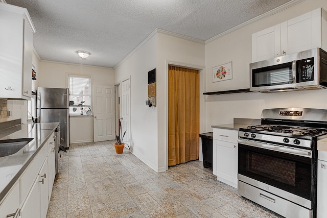 kitchen with white cabinets, crown molding, appliances with stainless steel finishes, and a textured ceiling