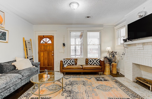 living room featuring wood-type flooring, a textured ceiling, a brick fireplace, and ornamental molding