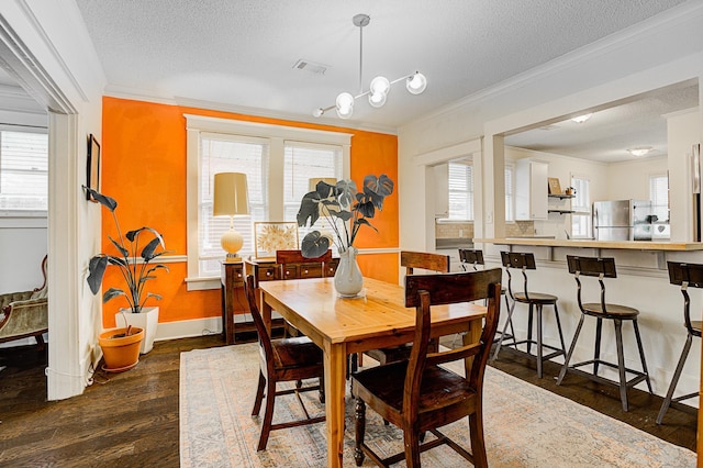 dining room featuring a textured ceiling, crown molding, and dark wood-type flooring