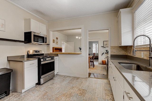 kitchen with a textured ceiling, stainless steel appliances, crown molding, sink, and white cabinets