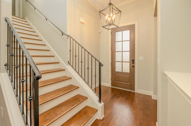 entrance foyer with ornamental molding, dark wood-type flooring, and a notable chandelier