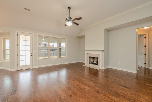 unfurnished living room featuring ceiling fan, dark wood-type flooring, crown molding, lofted ceiling, and a tiled fireplace