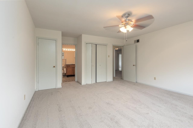 unfurnished bedroom featuring light carpet, ensuite bathroom, and ceiling fan