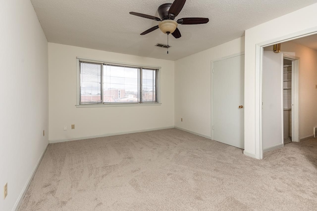 unfurnished bedroom featuring ceiling fan, light carpet, and a textured ceiling