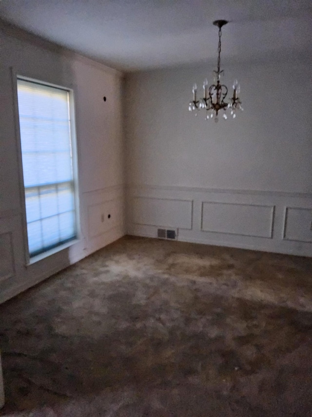 unfurnished dining area with a chandelier, dark carpet, and plenty of natural light