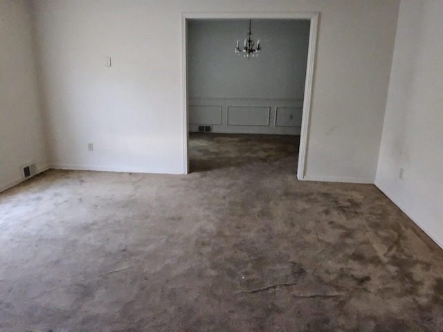 unfurnished room featuring dark carpet and an inviting chandelier