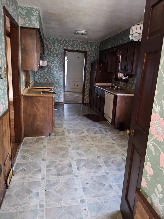 kitchen featuring a textured ceiling, dark brown cabinetry, white dishwasher, and sink