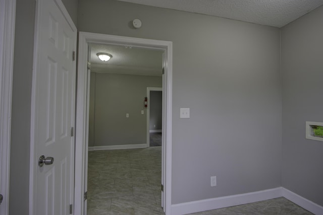 interior space with a textured ceiling and baseboards