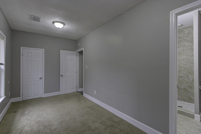 unfurnished bedroom with a textured ceiling, carpet floors, visible vents, and baseboards