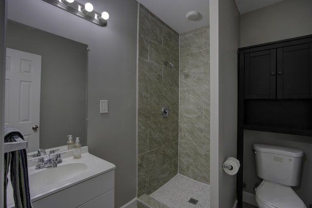 full bathroom with tiled shower, vanity, and toilet