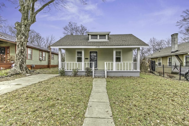 bungalow-style house with roof with shingles, a porch, a front lawn, and fence