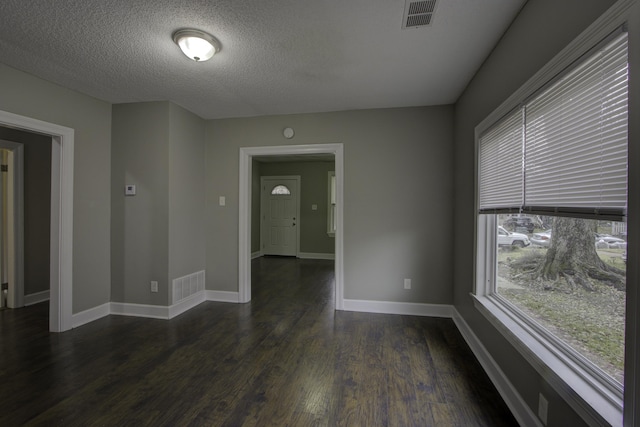 spare room featuring a textured ceiling and dark wood-type flooring