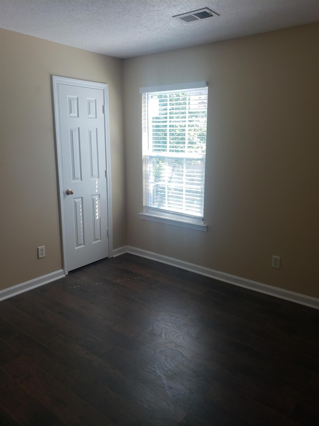 empty room featuring dark hardwood / wood-style floors and a textured ceiling