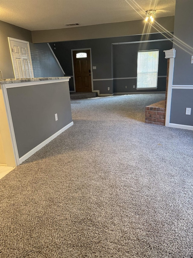 unfurnished living room featuring carpet and a textured ceiling