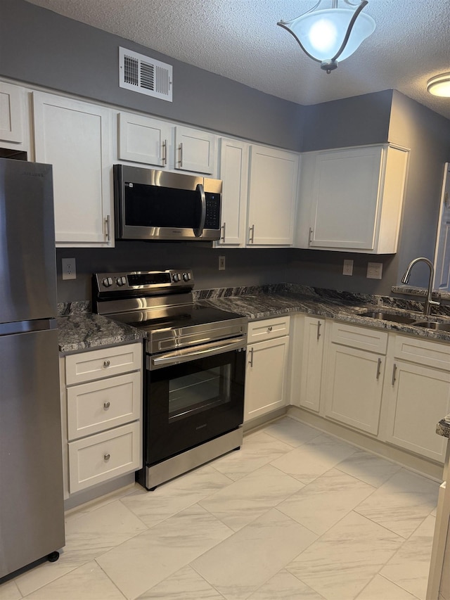 kitchen featuring white cabinets, sink, a textured ceiling, and appliances with stainless steel finishes